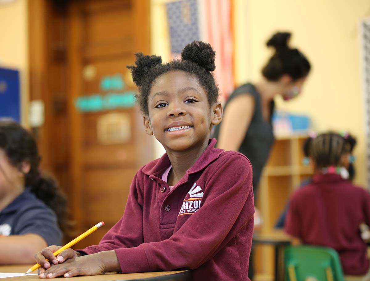 Elementary student smiling and posing together in a classroom.