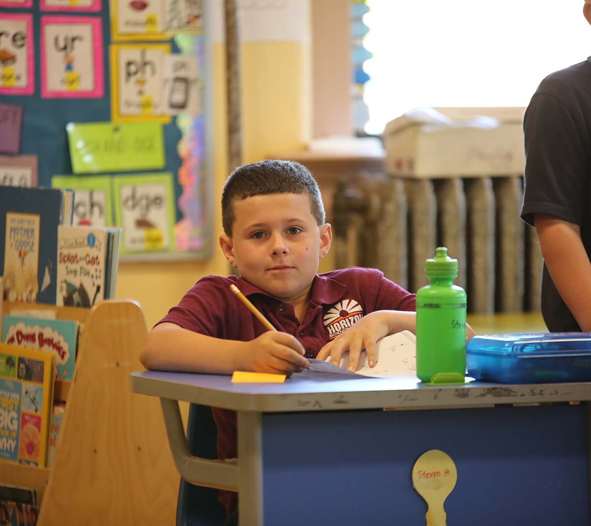 Student working on a notebook in a classroom.